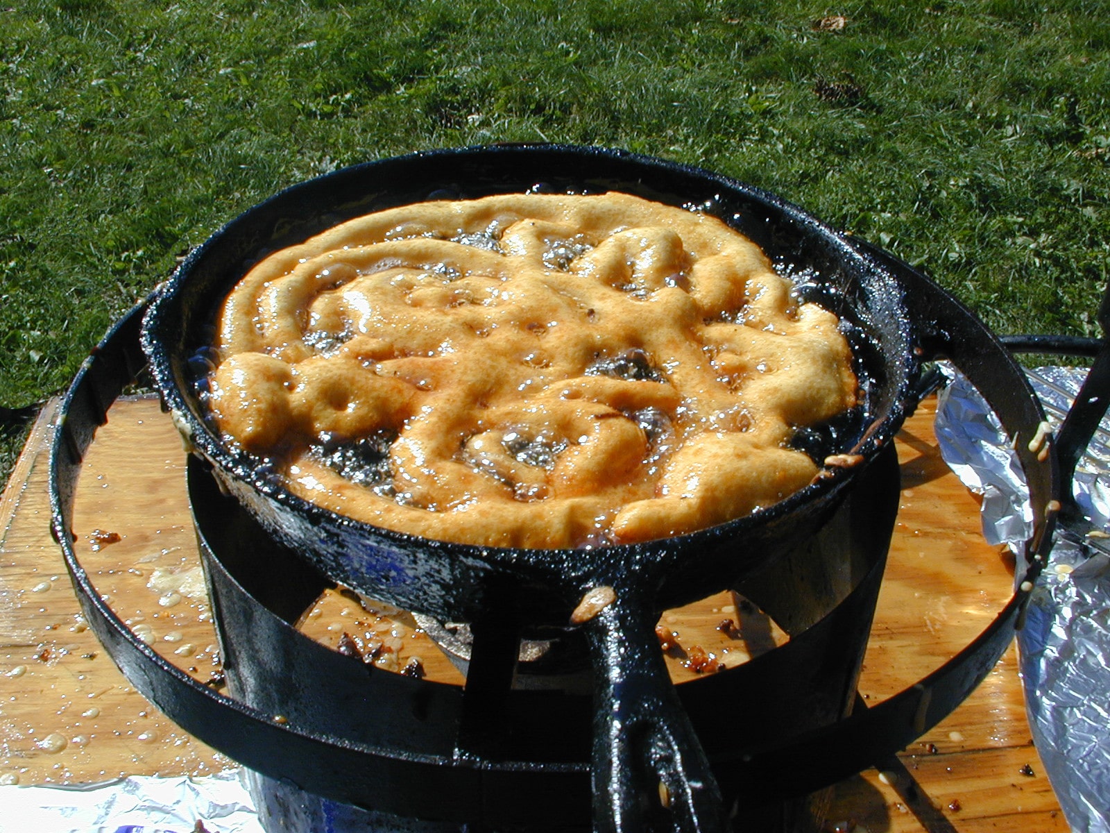 A funnel cake frying in a pan of oil.