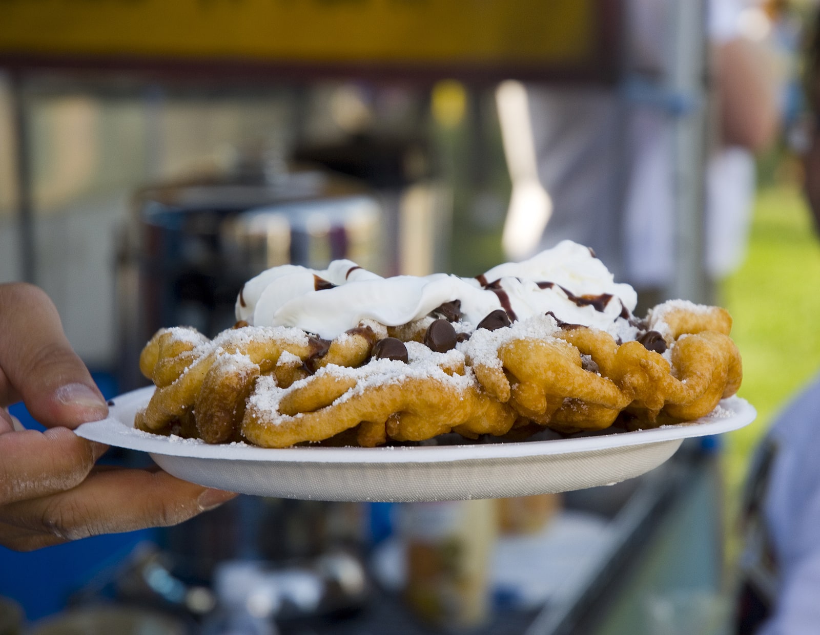 Funnel cake with whipped cream and chocolate on a plate.