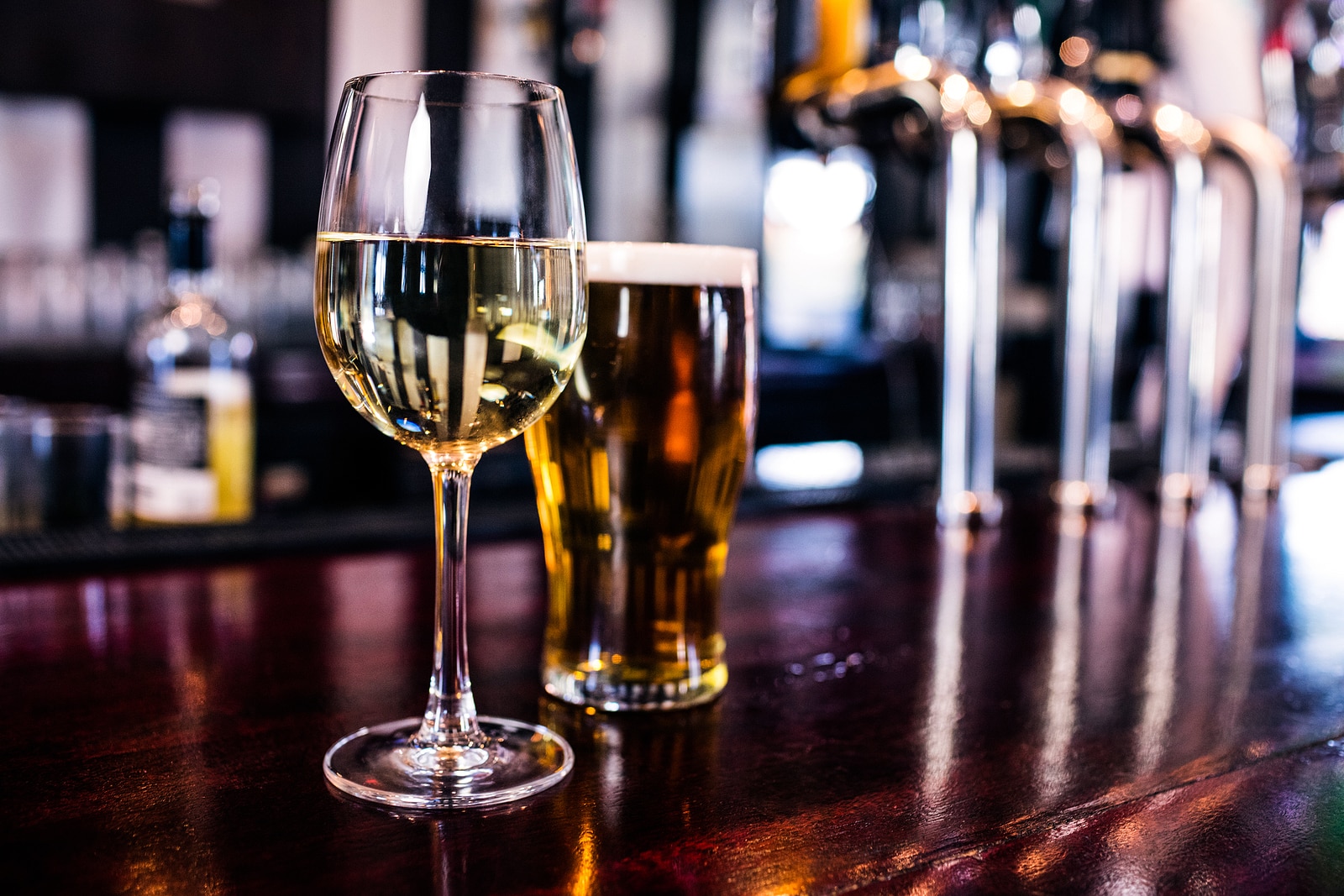 Close up of a glass of wine and a beer in a bar.