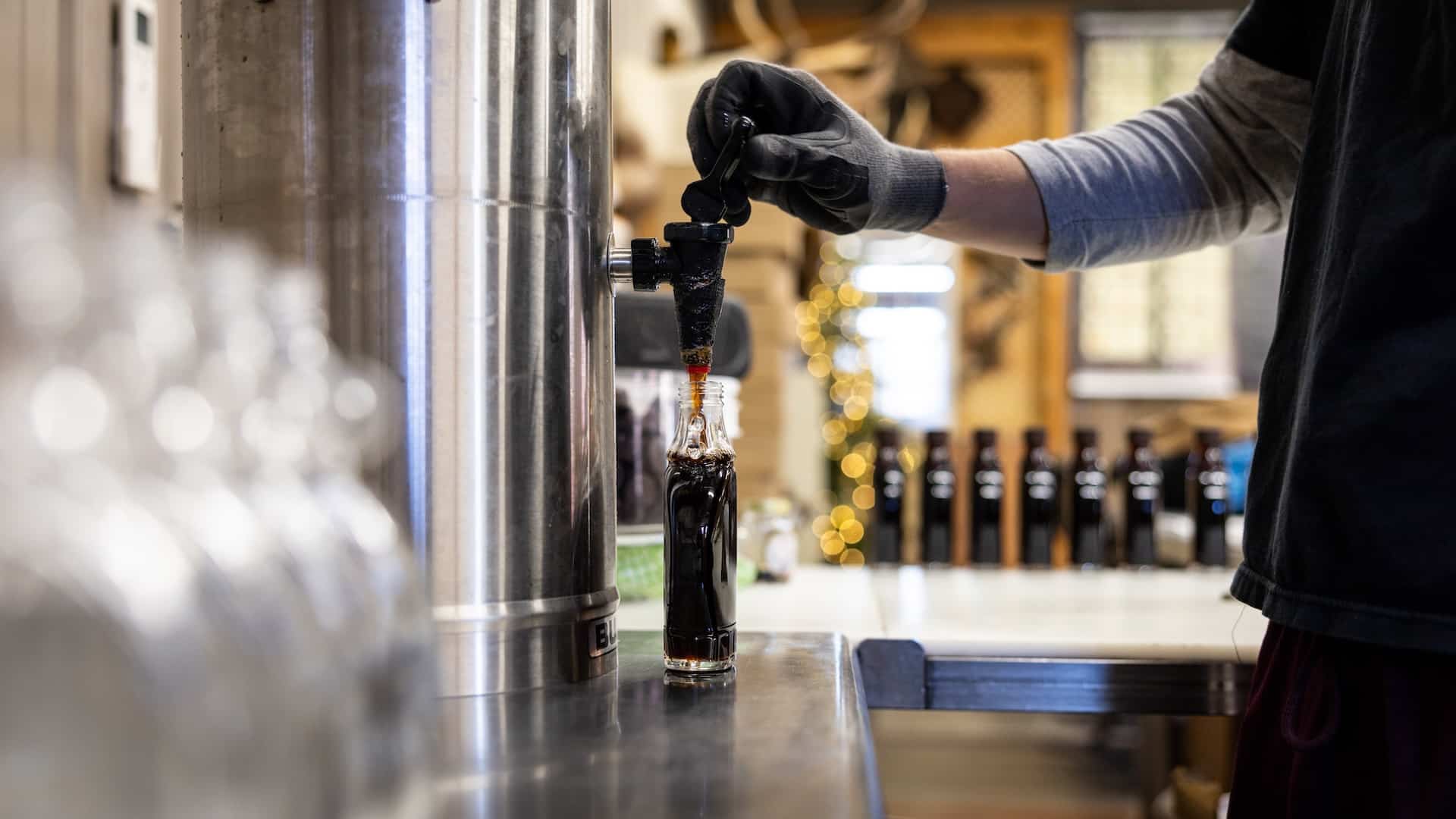 A man filling a bottle with hickory syrup.