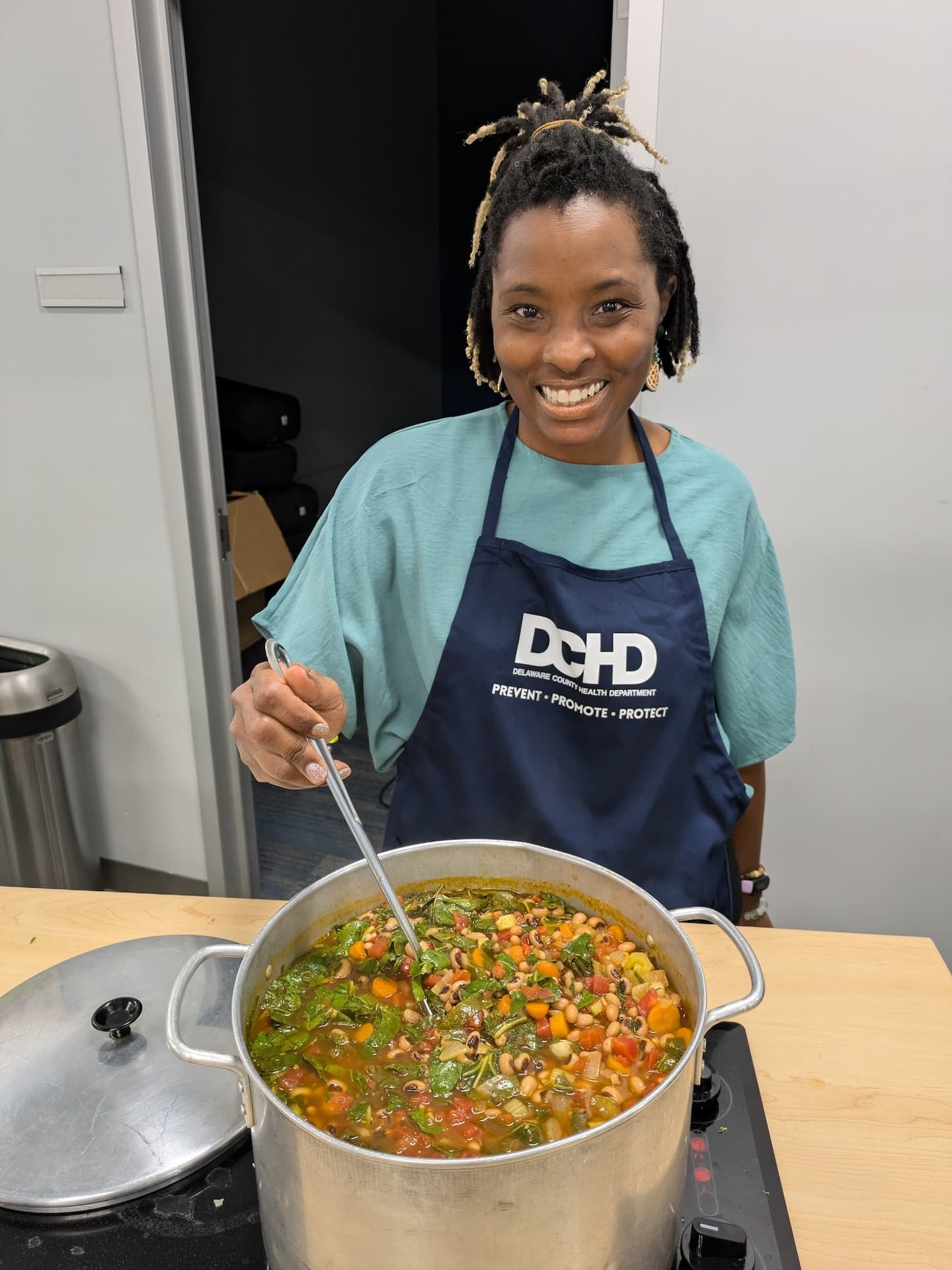 Stacey Woodson cooking stew with greens, beans and other vegetables.