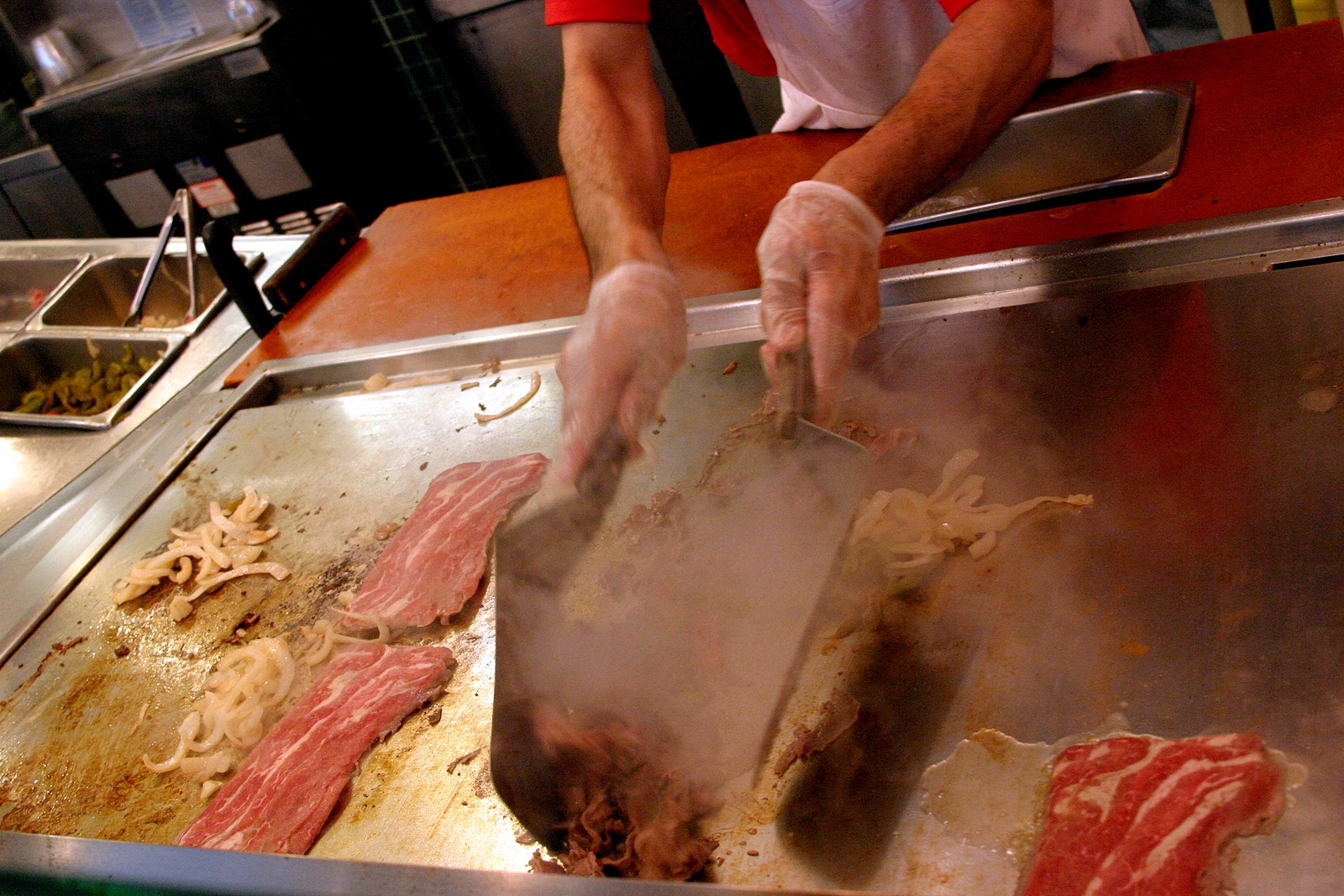 A man cooking a cheesesteak.