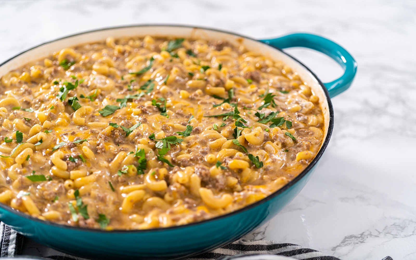 Cooking homemade hamburger helper in enameled cast iron skillet.